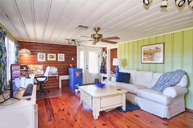 living room with french doors, ceiling fan, hardwood / wood-style floors, and wood walls