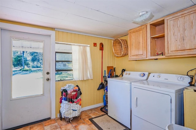 laundry area with cabinets, washing machine and dryer, and wooden walls