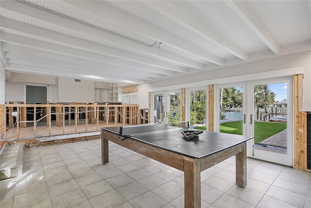 recreation room with beam ceiling, french doors, light tile patterned flooring, and a water view