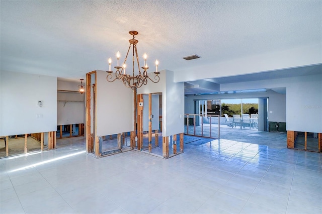 tiled empty room with a textured ceiling and a notable chandelier