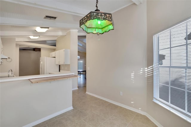 kitchen featuring light tile patterned floors, white refrigerator, decorative light fixtures, white cabinets, and vaulted ceiling with beams