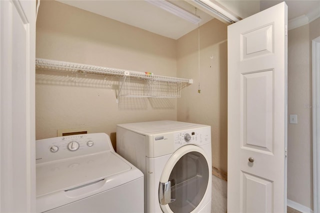 laundry room featuring washing machine and clothes dryer and crown molding