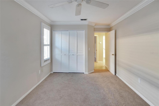 unfurnished bedroom featuring ceiling fan, ornamental molding, light carpet, and a closet