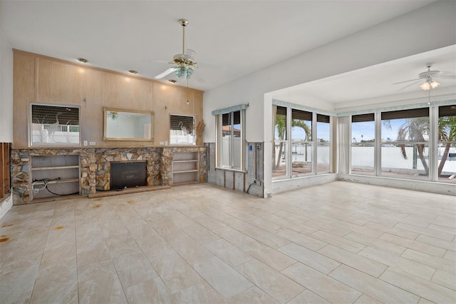 unfurnished living room with ceiling fan and wood walls