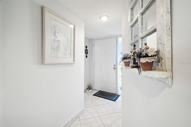 doorway with a textured ceiling and light tile patterned flooring