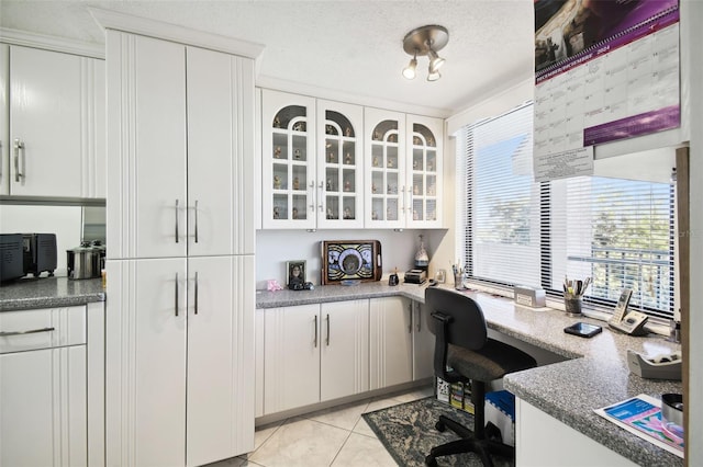 home office featuring light tile patterned flooring, built in desk, and a textured ceiling