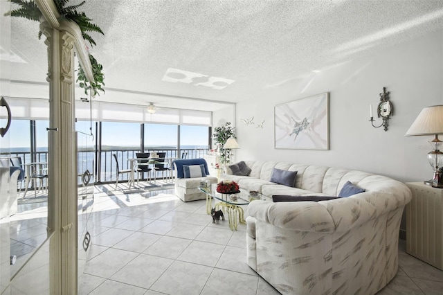 living room featuring light tile patterned floors, a water view, and a textured ceiling