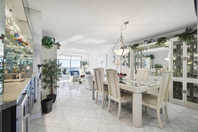 dining room featuring sink, light tile patterned flooring, and a textured ceiling