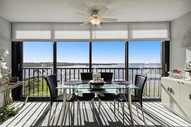 sunroom / solarium featuring a water view and ceiling fan