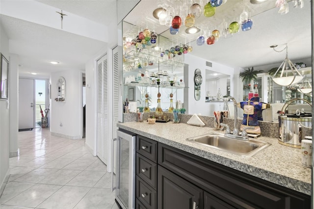 kitchen featuring a textured ceiling, light tile patterned flooring, sink, and beverage cooler