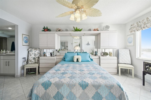 tiled bedroom with ceiling fan, ensuite bathroom, and a textured ceiling