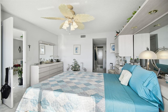 tiled bedroom featuring ceiling fan and a textured ceiling