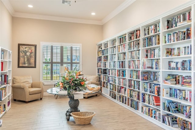 sitting room with light wood-type flooring and ornamental molding