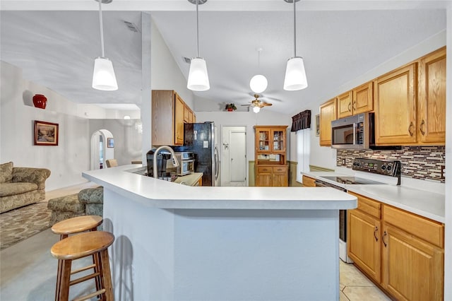 kitchen with a kitchen breakfast bar, backsplash, stainless steel appliances, ceiling fan, and pendant lighting