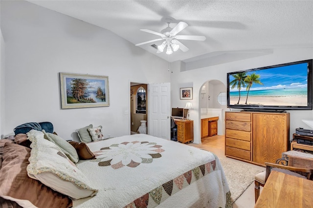 carpeted bedroom with a textured ceiling, ensuite bathroom, vaulted ceiling, and ceiling fan