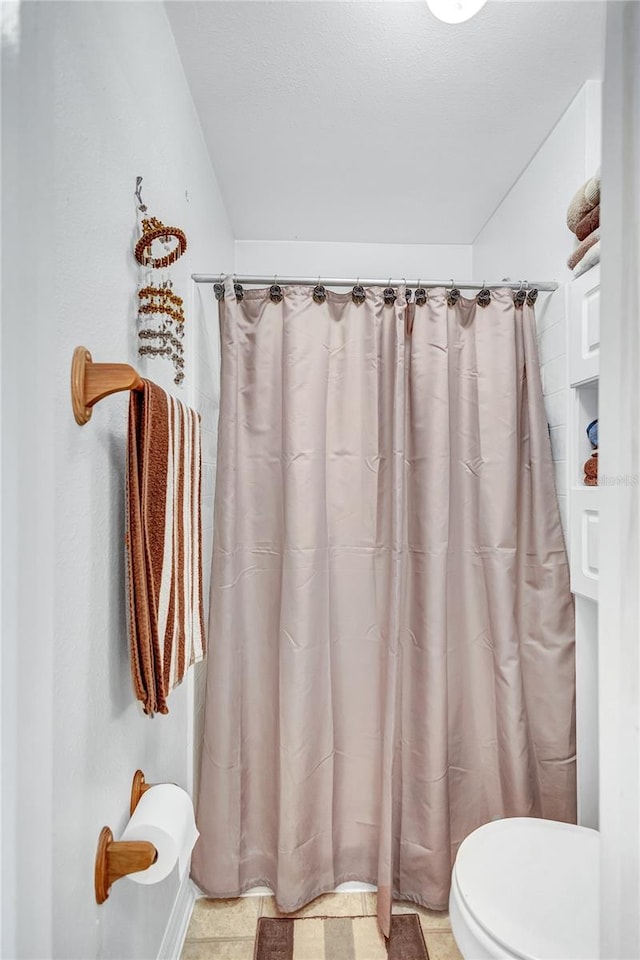 bathroom with tile patterned floors, a shower with shower curtain, and toilet