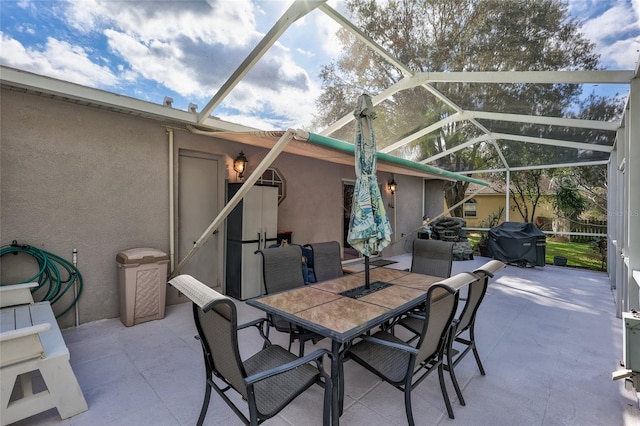 view of patio featuring glass enclosure and a grill