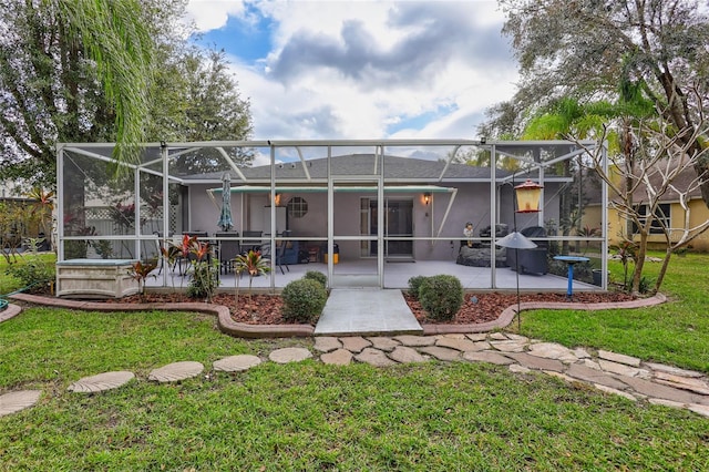 back of property featuring glass enclosure, a patio area, and a yard