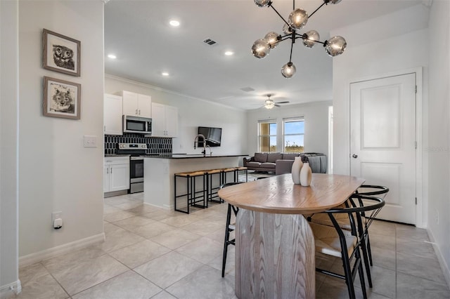 tiled dining room featuring ceiling fan with notable chandelier, ornamental molding, and sink