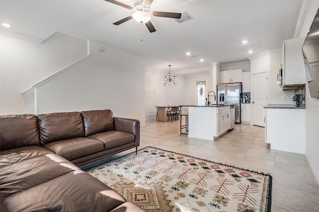 living room with light tile patterned flooring, ceiling fan with notable chandelier, crown molding, and sink