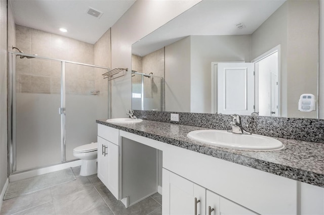 bathroom featuring tile patterned flooring, vanity, toilet, and a shower with door