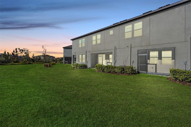 back house at dusk featuring a yard