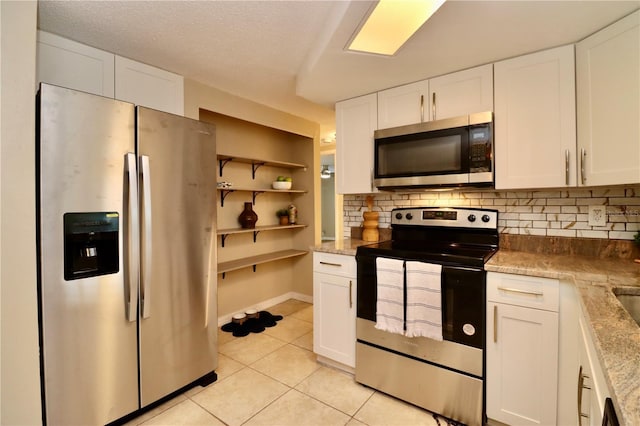 kitchen with tasteful backsplash, white cabinetry, light tile patterned floors, and appliances with stainless steel finishes