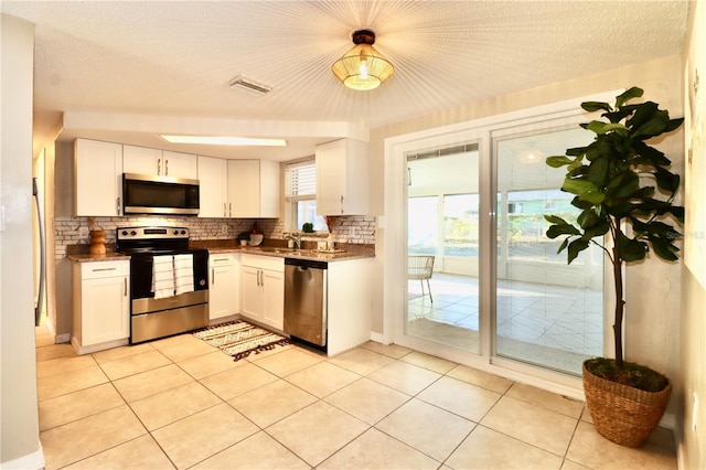 kitchen featuring sink, white cabinetry, stainless steel appliances, and light tile patterned floors