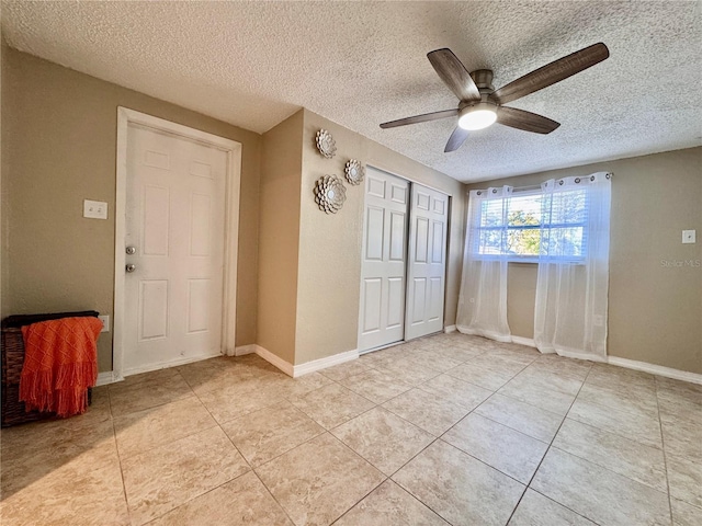 interior space with ceiling fan, light tile patterned floors, and a textured ceiling