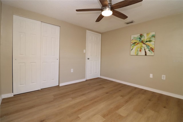 unfurnished bedroom featuring ceiling fan, light hardwood / wood-style floors, a textured ceiling, and a closet