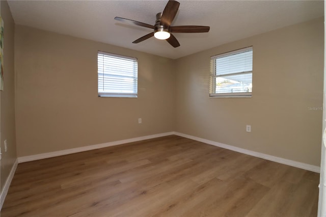 spare room with ceiling fan, a healthy amount of sunlight, and light hardwood / wood-style floors