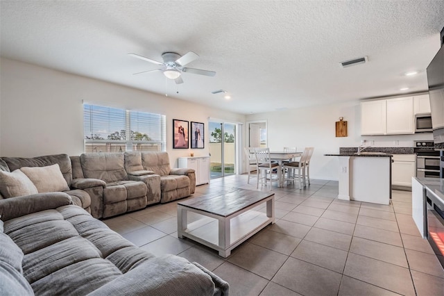 tiled living room with ceiling fan and a textured ceiling