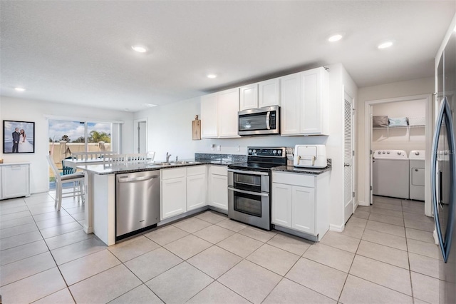 kitchen with kitchen peninsula, appliances with stainless steel finishes, sink, separate washer and dryer, and white cabinets