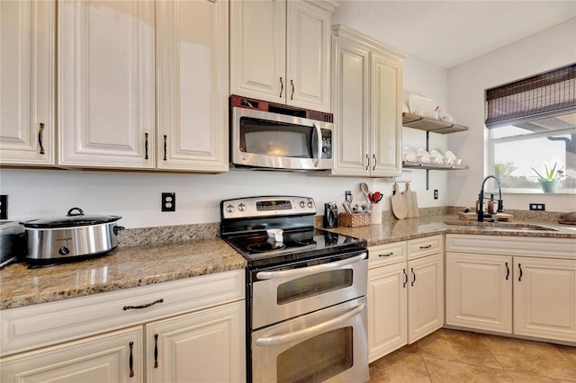 kitchen with light stone counters, appliances with stainless steel finishes, sink, and light tile patterned floors