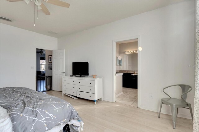 bedroom featuring ceiling fan, ensuite bath, and light wood-type flooring