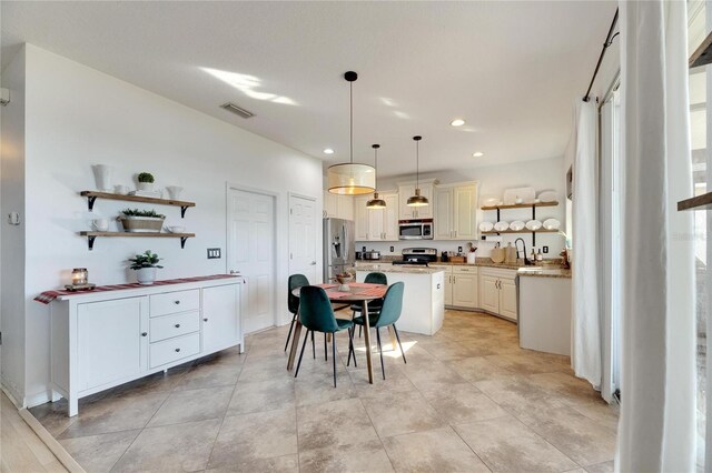 kitchen with sink, a breakfast bar area, appliances with stainless steel finishes, a center island, and decorative light fixtures