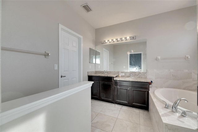 bathroom with tiled tub, vanity, and tile patterned floors