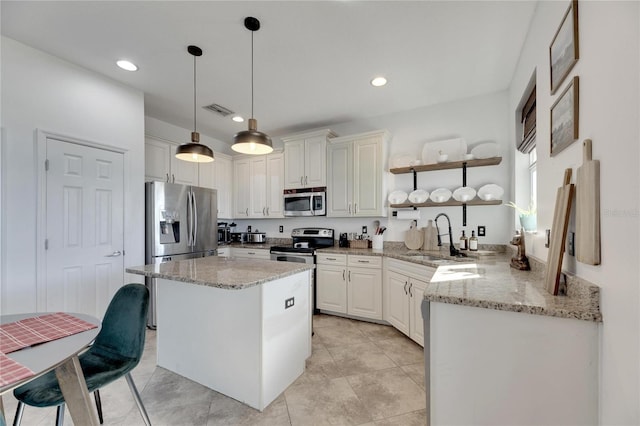 kitchen with sink, stainless steel appliances, light stone countertops, white cabinets, and decorative light fixtures