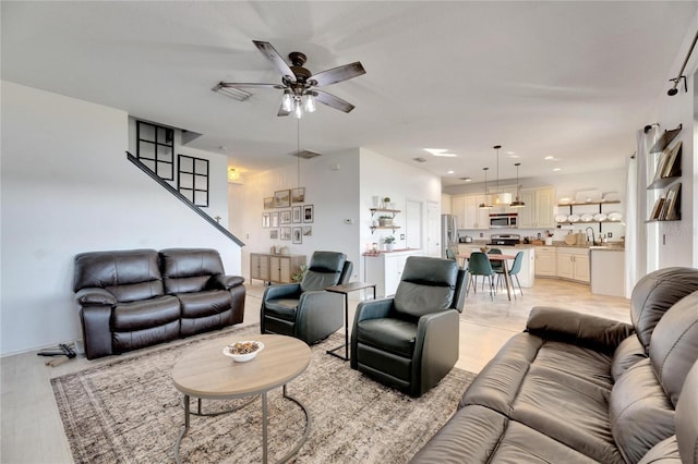 living room featuring sink, light hardwood / wood-style flooring, and ceiling fan