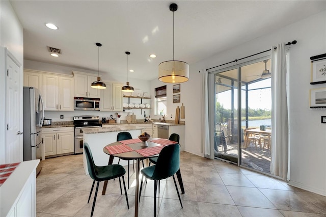 kitchen featuring light stone counters, stainless steel appliances, hanging light fixtures, and light tile patterned floors