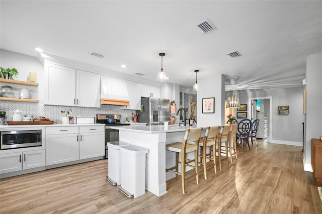 kitchen with a center island with sink, white cabinets, and stainless steel appliances