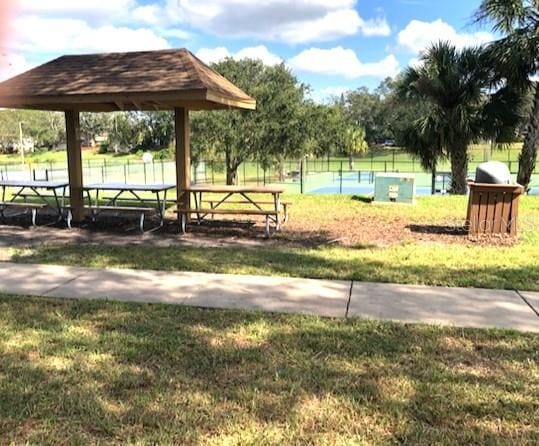 view of property's community featuring a gazebo, a yard, and tennis court