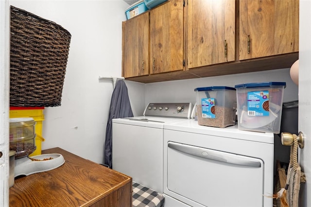 clothes washing area featuring cabinets and separate washer and dryer