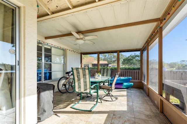 sunroom featuring beam ceiling and ceiling fan