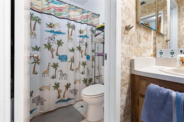 bathroom with tile patterned flooring, vanity, toilet, and walk in shower