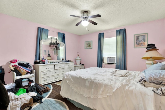 bedroom featuring hardwood / wood-style flooring, ceiling fan, cooling unit, and a textured ceiling