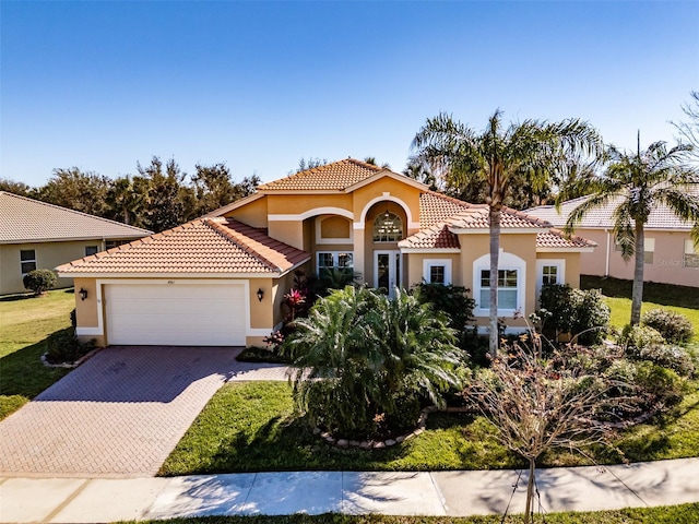 mediterranean / spanish-style home featuring a front lawn and a garage