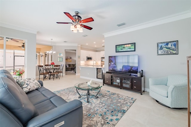 living room featuring ceiling fan with notable chandelier, sink, and ornamental molding