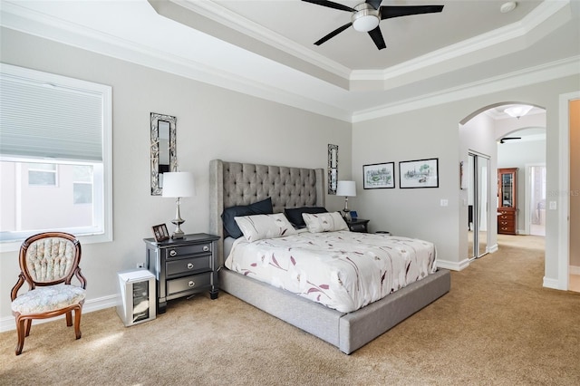 bedroom featuring ceiling fan, light colored carpet, a tray ceiling, and crown molding