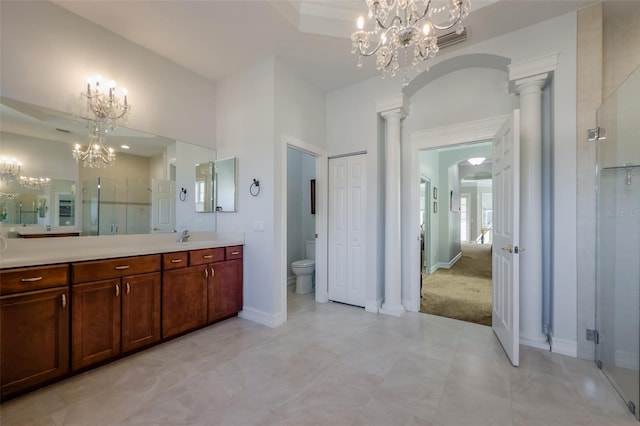 bathroom with toilet, an inviting chandelier, an enclosed shower, and decorative columns